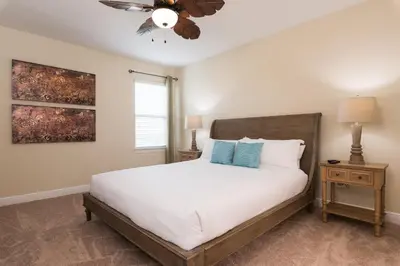 a bedroom with a white bed and a ceiling fan at Luxury Disney Dreams Home with Pool, Spa & Game Room in Orlando
