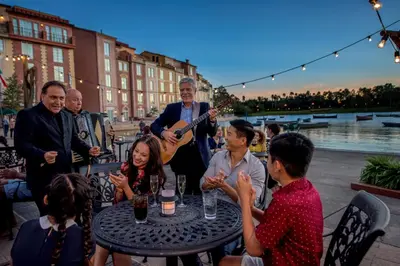 a group of people sitting around a table playing guitar at Universal's Loews Portofino Bay Hotel in Orlando