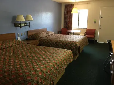 a hotel room with two beds and a chair at Flamingo Inn in Kissimmee