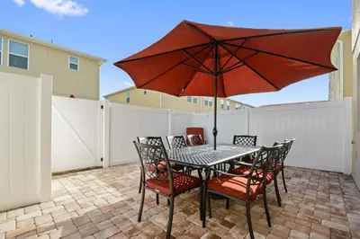 a table and chairs with an umbrella on a patio at Four Bedrooms Townhome 5126K in Kissimmee