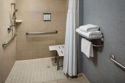 a bathroom with a shower and a sink and towels at Hyatt Place Lake Mary/Orlando North in Lake Mary