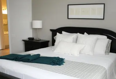 a bed with white pillows and a green towel on it at Shoreway Condo #231521 in Orlando