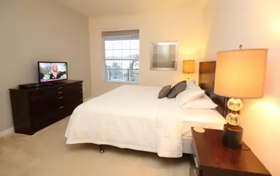 a bedroom with a white bed and a television at Shoreway Condo #231531 in Orlando