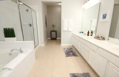 a white bathroom with two sinks and a shower at Cayview Condo #231541 in Orlando