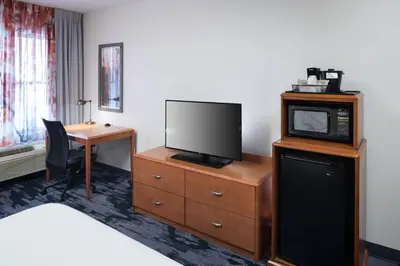 a hotel room with a television on a dresser with a desk at Fairfield Inn Suites by Marriott Orlando At SeaWorld in Orlando