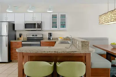 a kitchen with a counter with two green chairs at Marriott's Harbour Lake in Orlando