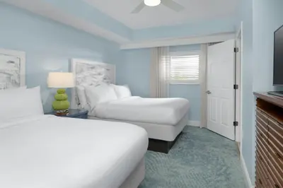 a white hotel room with two beds and a tv at Marriott's Harbour Lake in Orlando