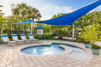 a swimming pool with chairs and a blue umbrella at Marriott's Royal Palms in Orlando