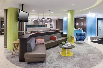a lobby with a couch and a tv in a room at SpringHill Suites by Marriott Orlando at SeaWorld in Orlando