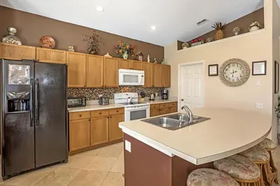 a kitchen with a sink and a refrigerator at Sun Palm Disney Villa in Kissimmee