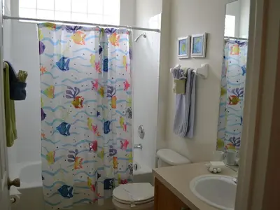 a bathroom with a shower curtain with a toilet and a sink at Sun Palm Disney Villa in Kissimmee