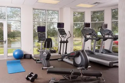 a gym with treadmills and exercise equipment and windows at SpringHill Suites Orlando Airport in Orlando