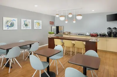 a kitchen with tables and chairs and a counter at TownePlace Suites by Marriott Orlando East/UCF Area in Orlando