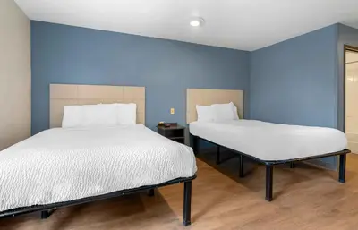 two beds in a room with blue walls at Extended Stay America Select Suites - Orlando - South in Orlando