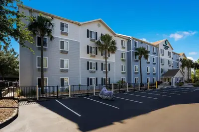 a large apartment building with a parking lot with palm trees at WoodSpring Suites Orlando West - Clermont in Clermont