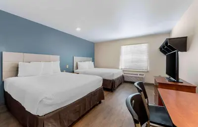 a hotel room with two beds and a desk and a television at Extended Stay America Select Suites - Orlando - East in Orlando