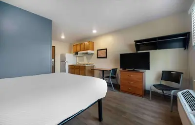 a room with a bed and a kitchen with a television at Extended Stay America Select Suites - Orlando - East in Orlando