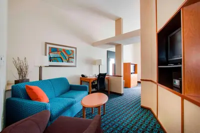 a hotel room with a blue couch and a desk at Fairfield Inn & Suites by Marriott Clermont in Clermont