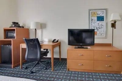 a hotel room with a desk and a television and a chair at Fairfield Inn & Suites by Marriott Clermont in Clermont