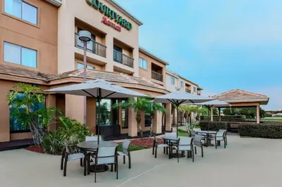 a group of tables with umbrellas outside of a hotel at Courtyard by Marriott Orlando Lake Mary North in Lake Mary