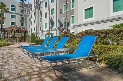 a row of blue lounge chairs in front of a building at Lake Buenavista Apartments close to Disney in Orlando