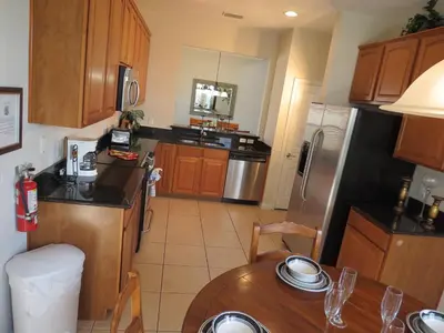 a kitchen with wooden cabinets and a wooden table with a tableablish at Formosa Garden Pool Home in Kissimmee