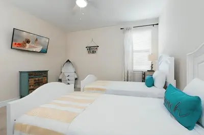 a white bedroom with two beds and a fireplace at Wilmington Loop 6 Br Luxury Villa with Pool and Spa in Orlando