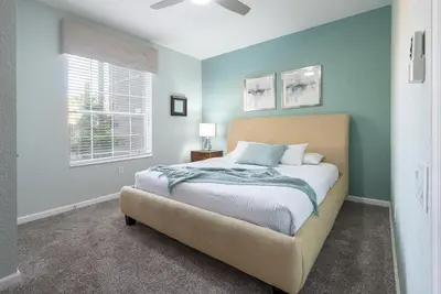 a bedroom with a bed with blue walls and a window at La Vista Lakeview Condo in Orlando