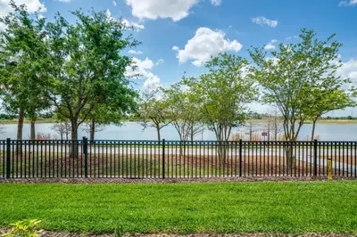 a black fence with trees and water in the background at La Vista Lakeview Condo in Orlando