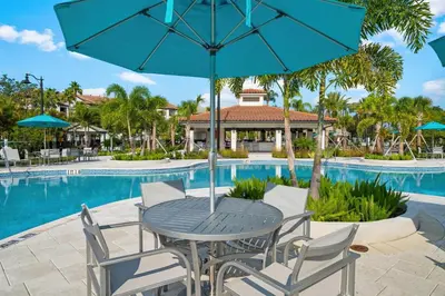 a table and chairs with an umbrella next to a pool at Miranda's Gem Condo in Orlando