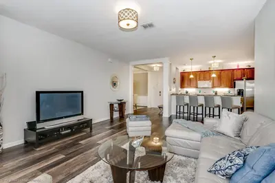 a living room with a white couch and a tv at Miranda's Gem Condo in Orlando