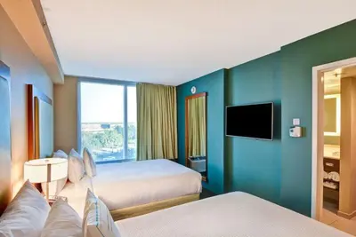 a hotel room with two beds and a flat screen tv at SpringHill Suites by Marriott Orlando Lake Buena Vista South in Kissimmee