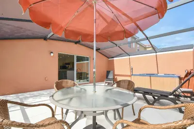 a table and chairs on a balcony with an umbrella at Three Bedrooms Townhome 3012 in Kissimmee