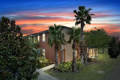 a house with palm trees in front of a sunset at Three Bedrooms Townhome 3012 in Kissimmee