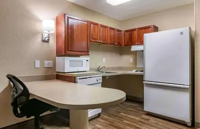 a kitchen with a table and a white refrigerator at Extended Stay America Suites - Orlando - Southpark - Commodity Circle in Orlando