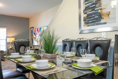 a dining room with a table with plates and wine glasses at Five Bedrooms TownHome with Pool 4849 in Kissimmee
