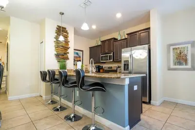 a kitchen with a counter and stools at a bar at Five Bedrooms TownHome with Pool 4849 in Kissimmee