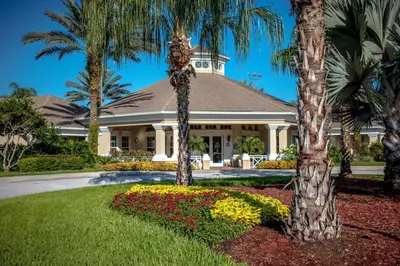 a house with palm trees and flowers in front of it at Windsor Palm Condo #213421 in Kissimmee