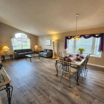 a living room with a table and chairs and a couch at Lake Berkley Home #213517 in Kissimmee