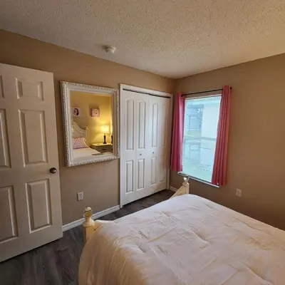 a bedroom with a bed and a mirror and a window at Lake Berkley Home #213517 in Kissimmee