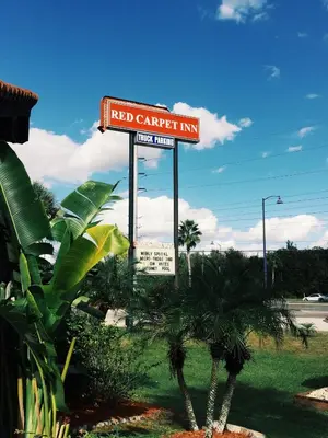 a red carpet inn sign in a field with palm trees at The keys in Kissimmee