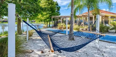 a hammock on the beach in front of a house at 5-Star Resort Villa with Private Pool, Minutes from Disney in Kissimmee