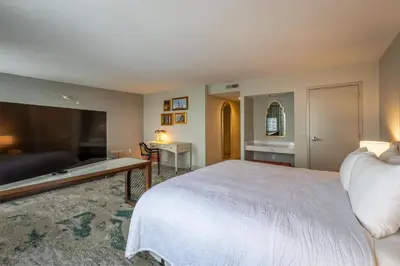 a bedroom with a large white bed and a desk at Castle Hotel, Autograph Collection in Orlando