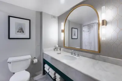 a bathroom with a sink and a toilet and a mirror at Castle Hotel, Autograph Collection in Orlando