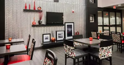 a restaurant with tables and chairs and a flat screen tv at Hampton Inn & Suites Orlando-John Young Parkway/South Park in Orlando