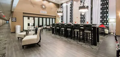 a restaurant with a long bar with chairs and tables at Hampton Inn & Suites Orlando-John Young Parkway/South Park in Orlando