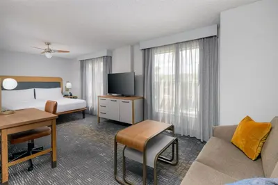 a hotel room with a bedroom with a bed and a desk at Homewood Suites by Hilton Orlando-UCF Area in Orlando