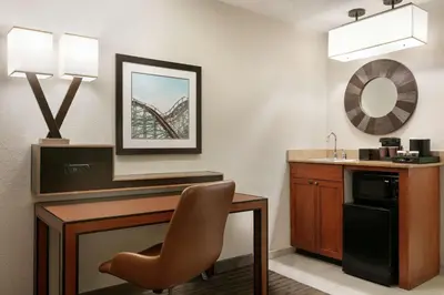 a hotel room with a desk and a chair at Embassy Suites by Hilton Orlando International Drive ICON Park in Orlando