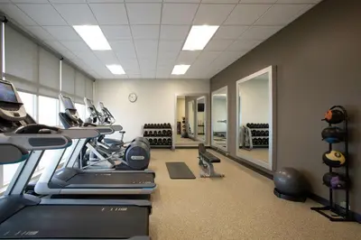 a gym with treadmills and ellipticals in a room at Embassy Suites by Hilton Orlando Airport in Orlando