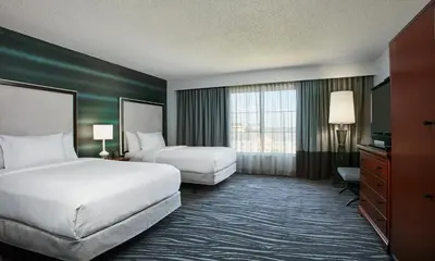a hotel room with two beds and a television at Embassy Suites by Hilton Orlando Airport in Orlando